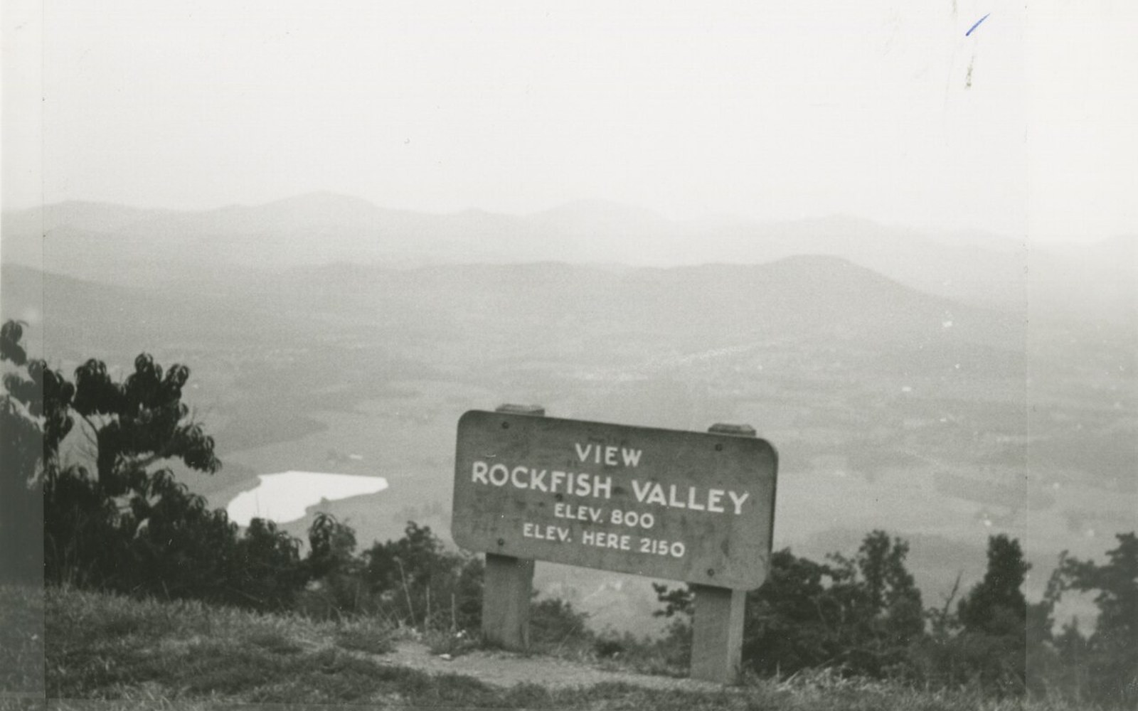 Wooden overlook sign for Rockfish Valley with hazy mountains and farmland below