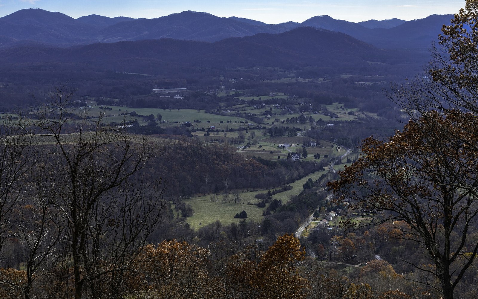 Aerial view of a valley with fields and a winding road framed by mountain ridges